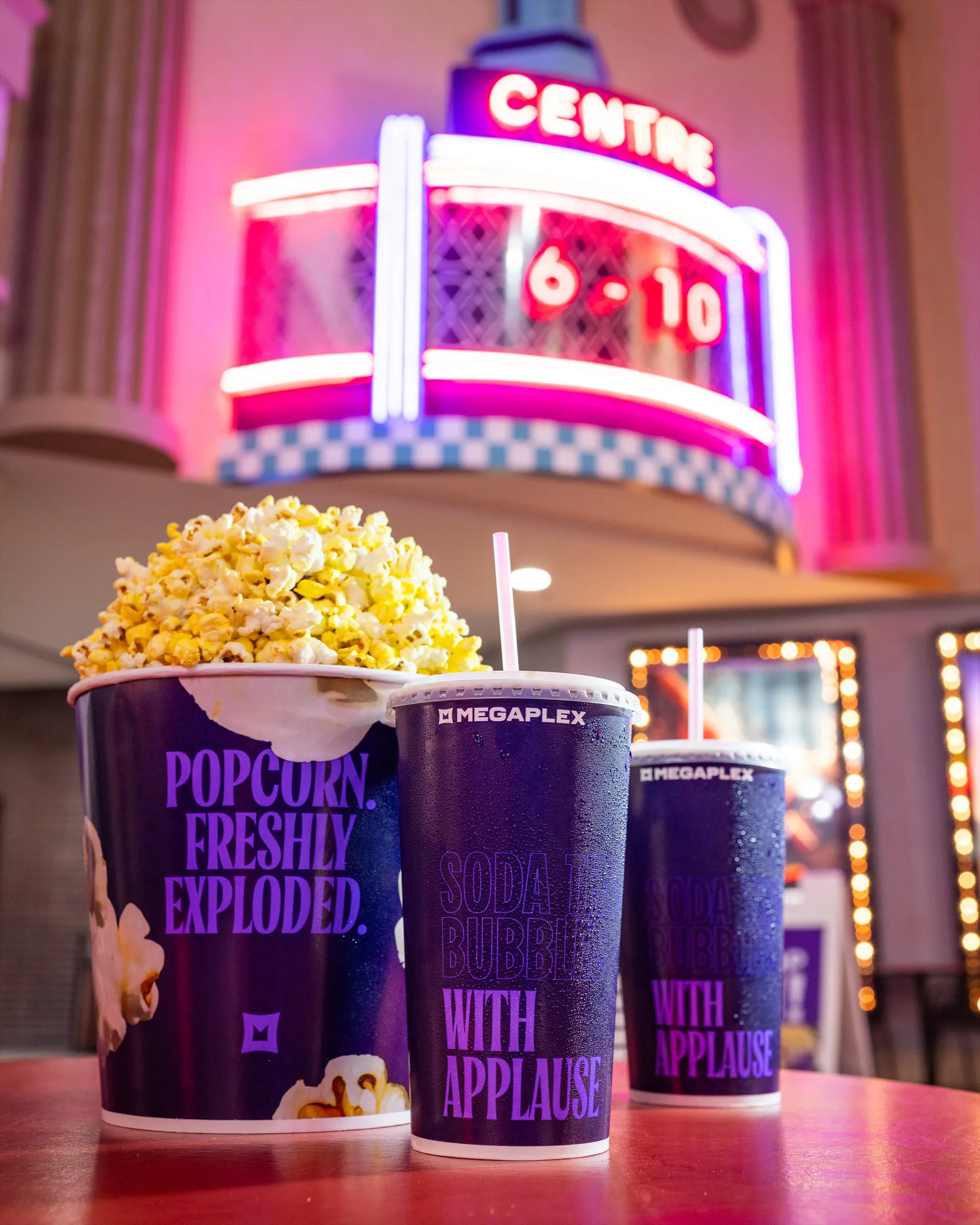 Popcorn and branded sodas under a neon theater marquee