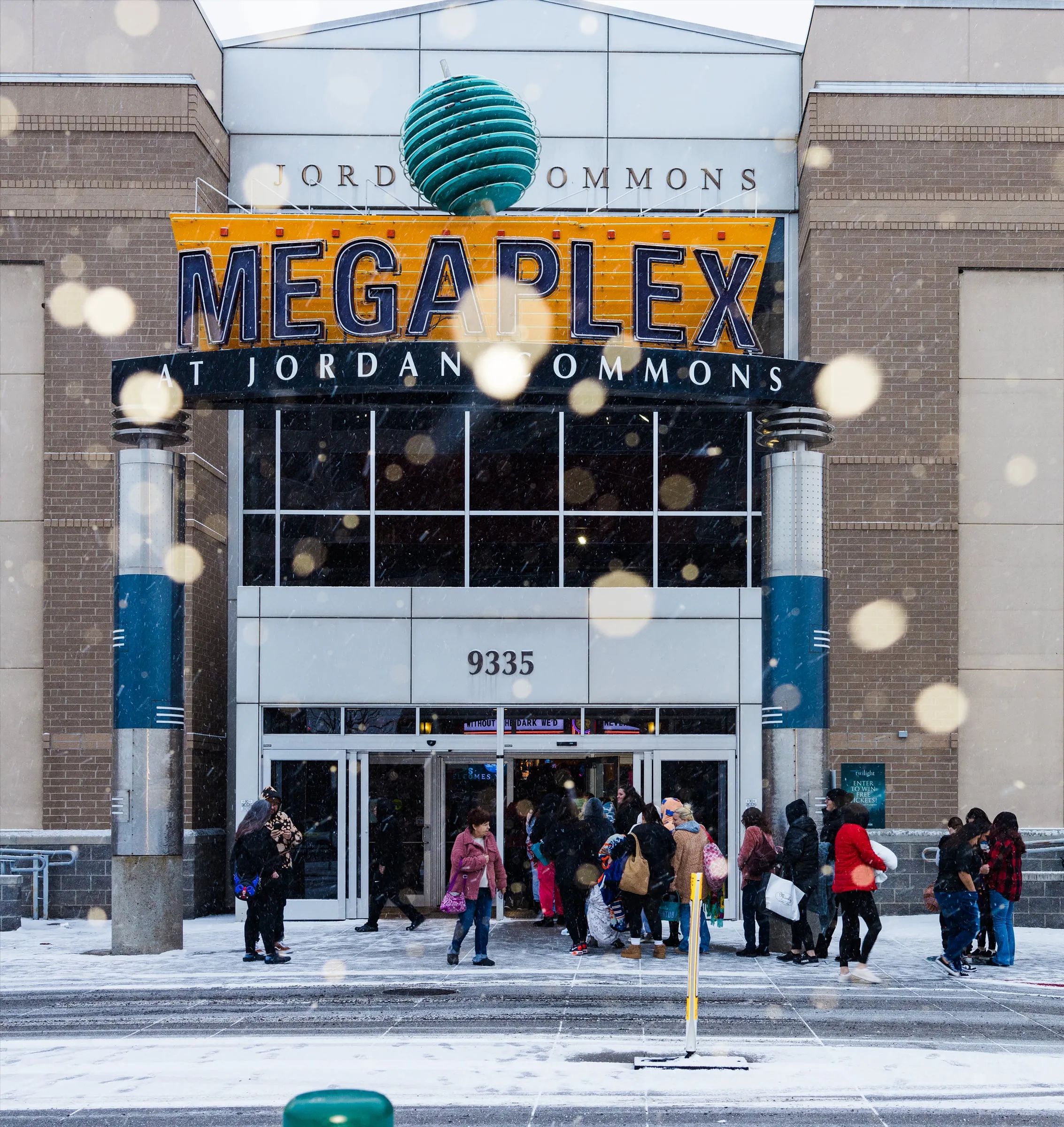 Crowd filing into the Megaplex entrance through falling snow