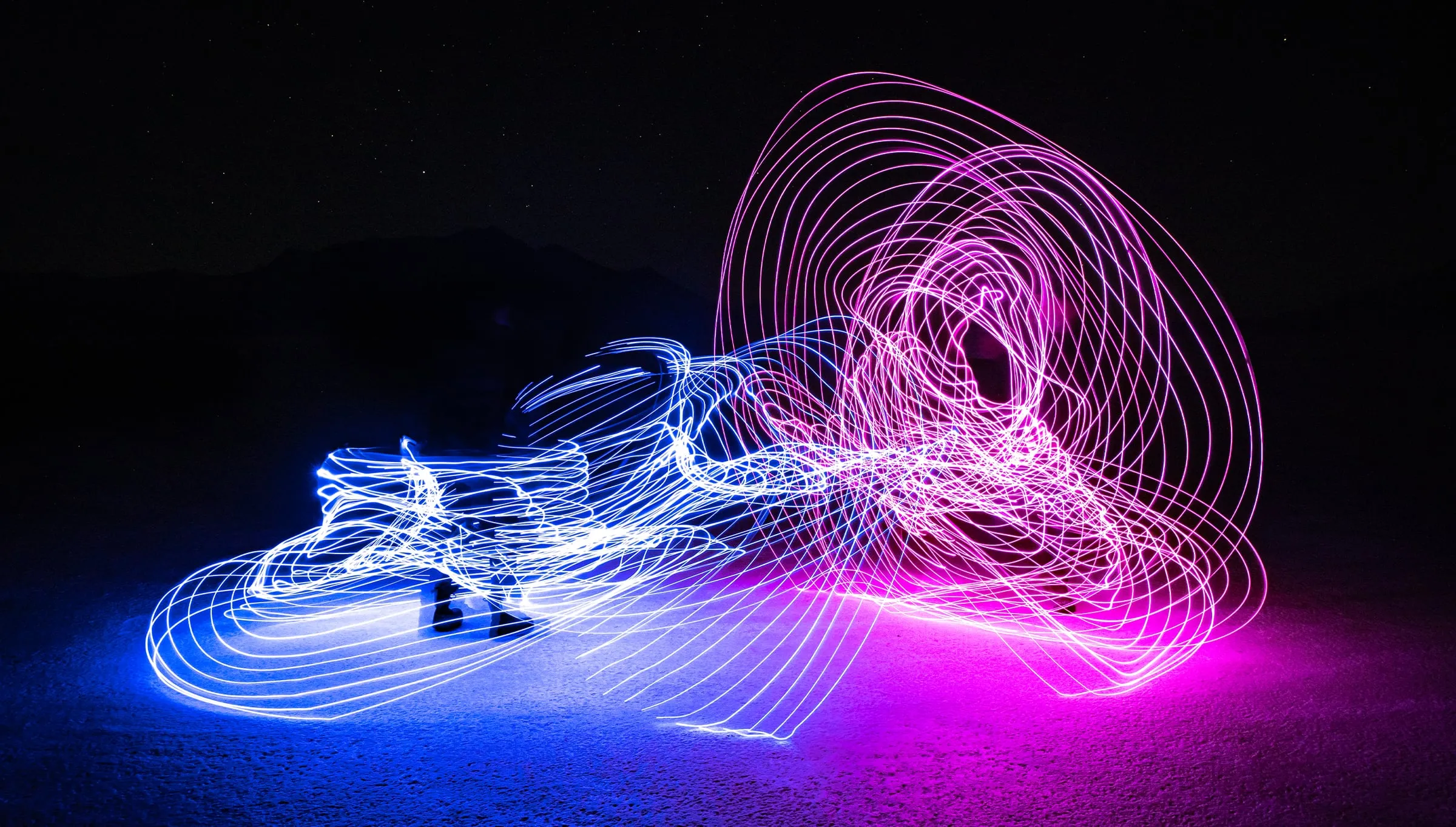 Blue and pink light-painted coils spun across a frozen lake at night