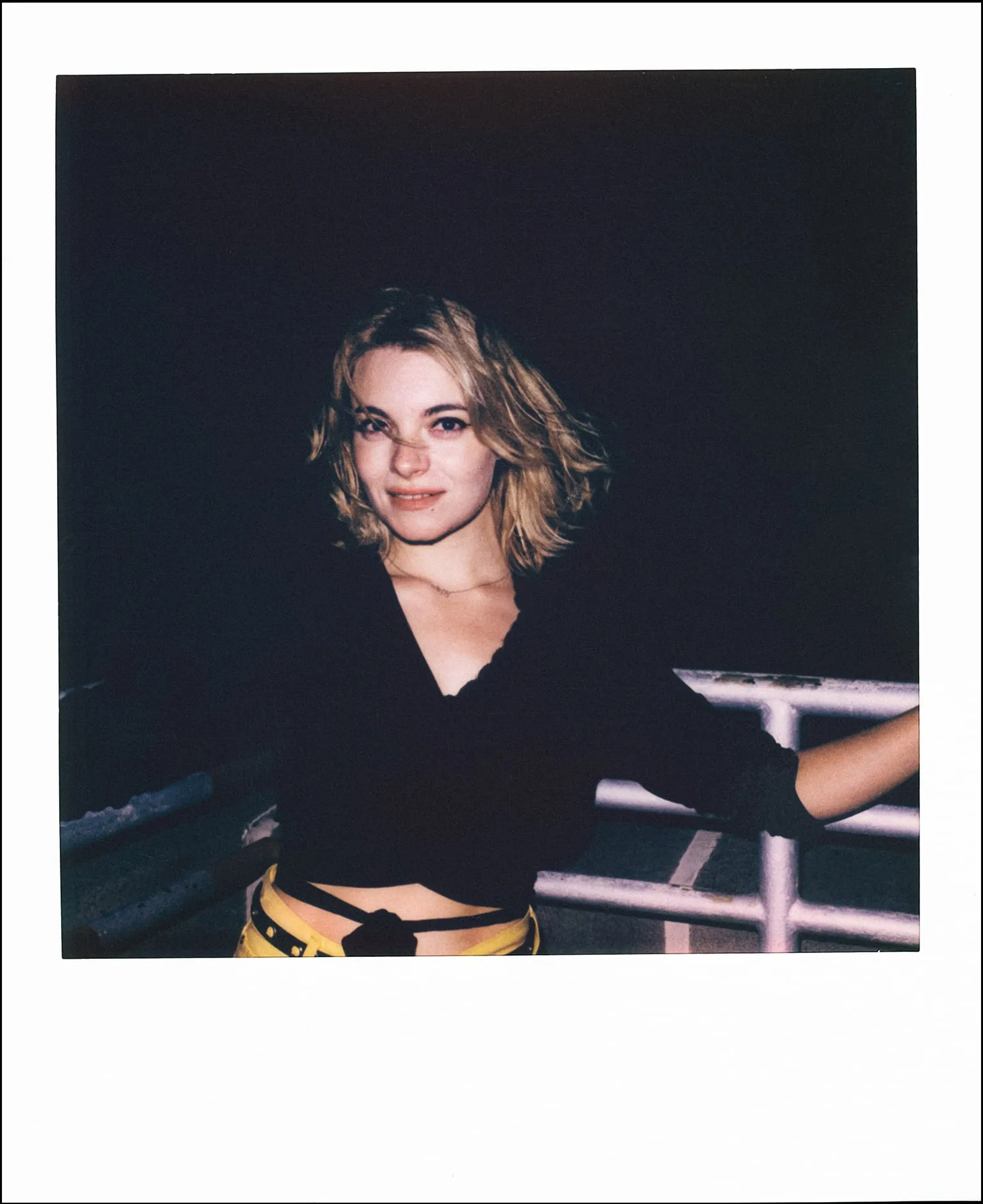Polaroid of a woman leaning back against a ferry railing at night