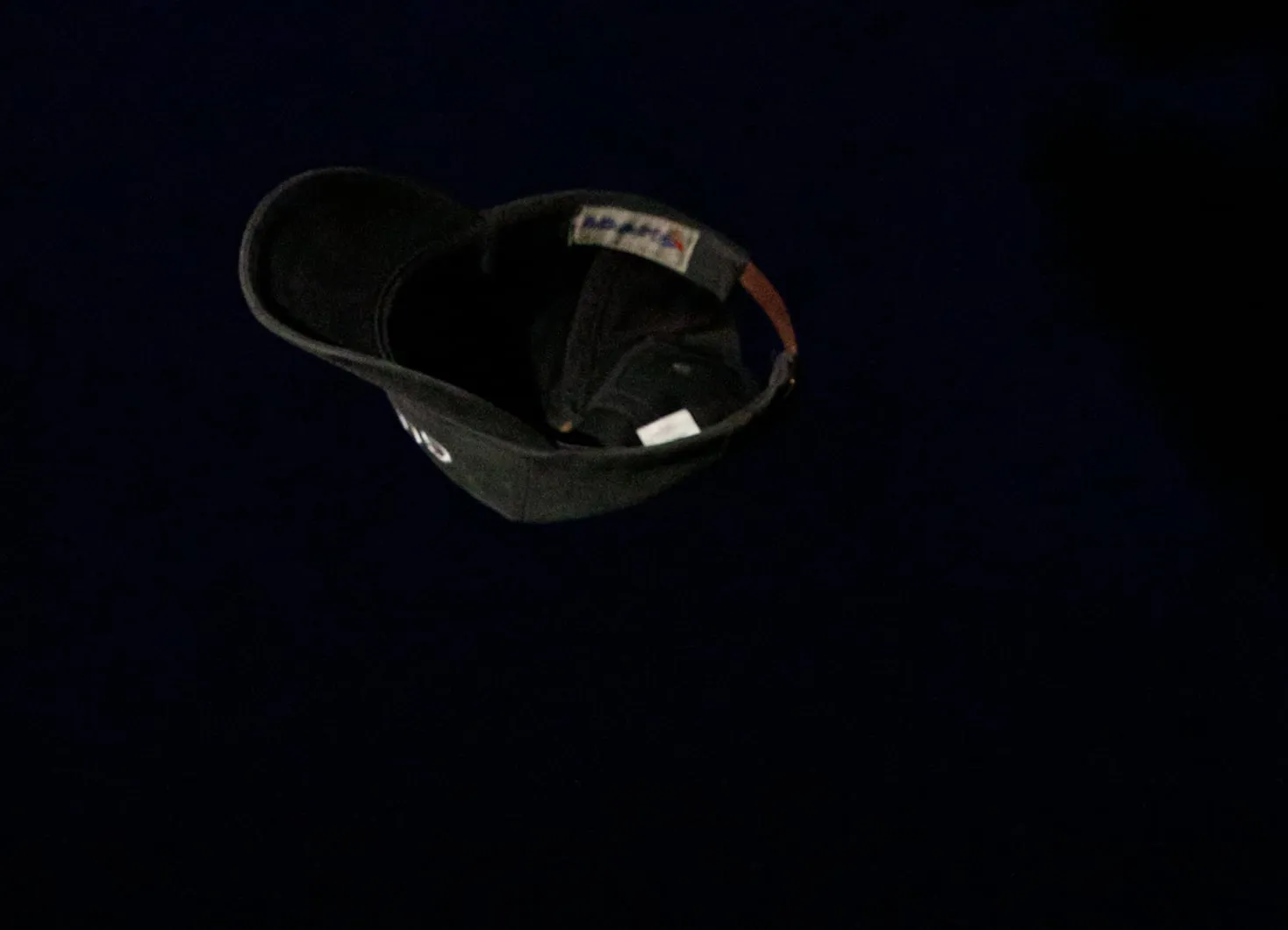 A baseball cap suspended mid-air in the dark