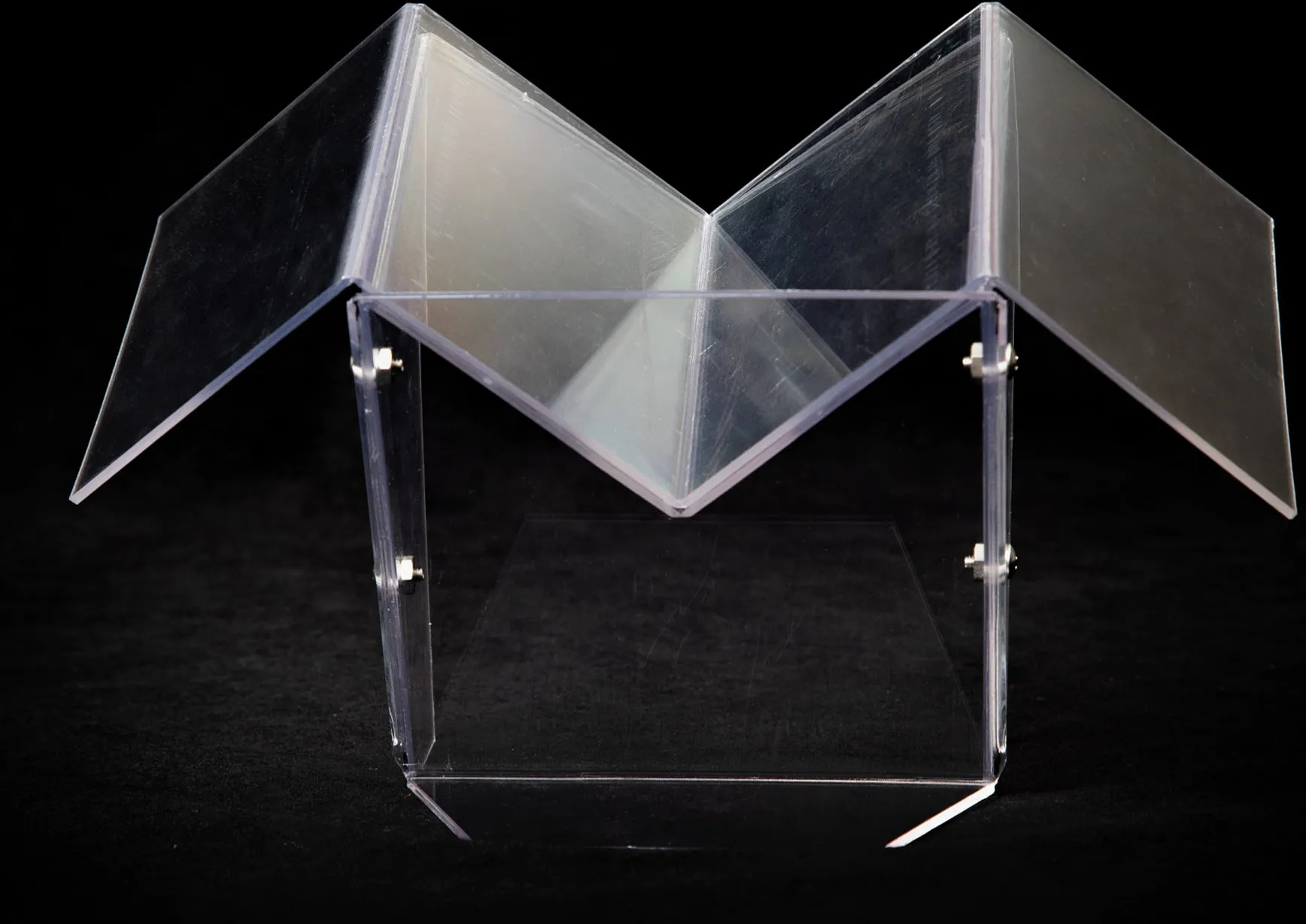 Folded clear acrylic stand photographed on black