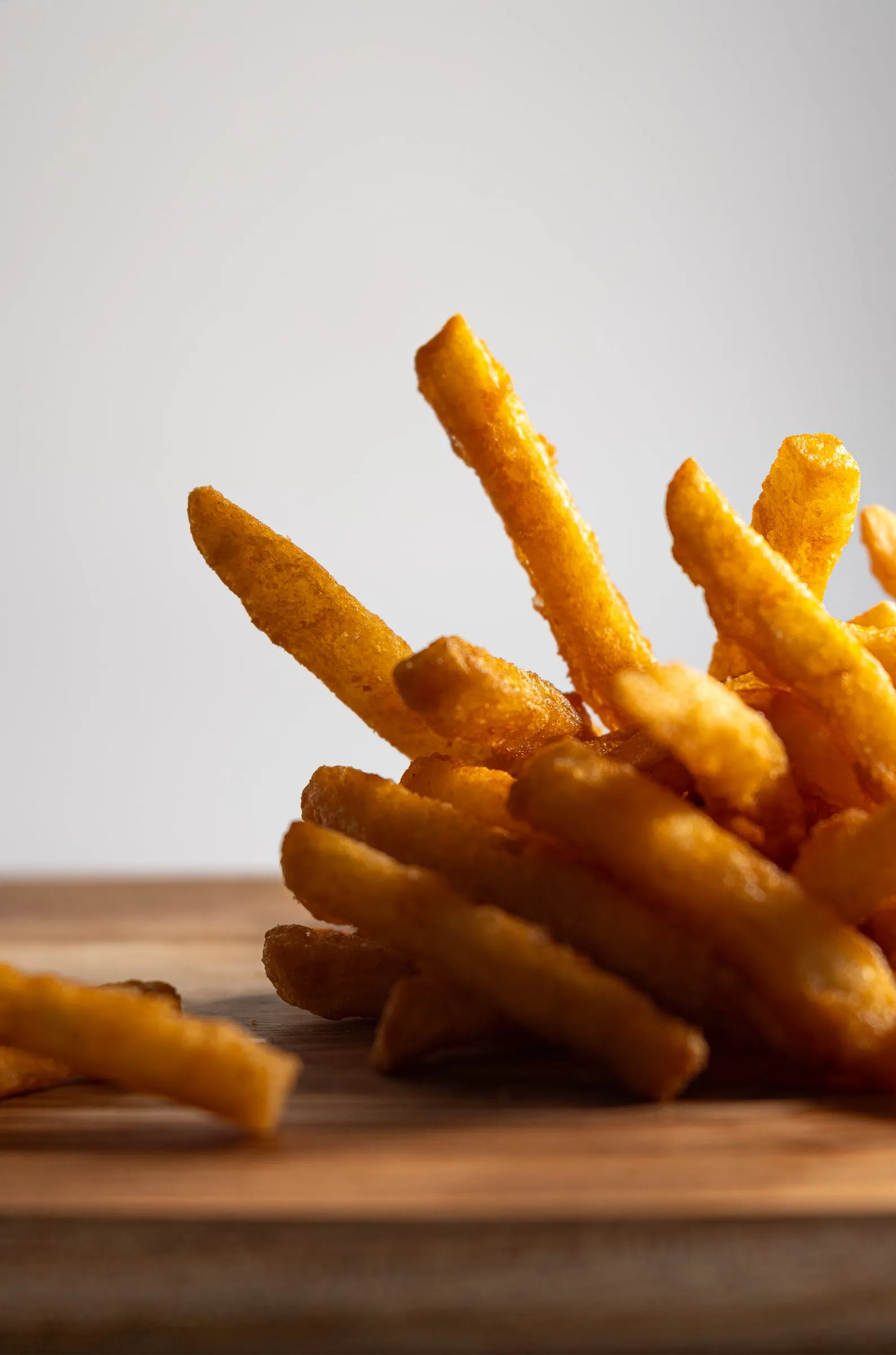 Crispy fries stacked on a wooden board