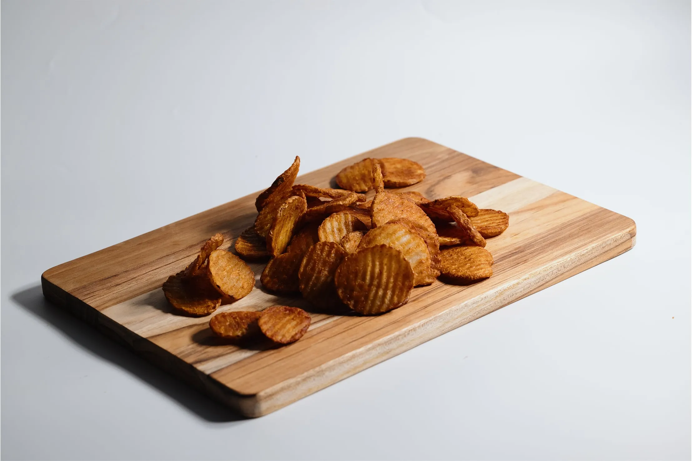 Ridged potato chips arranged on a small cutting board